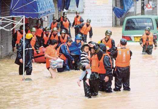SEORANG anggota penyelamat mendukung seorang kanak-kanak yang terperangkap dalam banjir selepas hujan lebat berpunca daripada Taufan Chan-hom melanda Shaoxing di wilayah Zhejiang, China, kelmarin. 