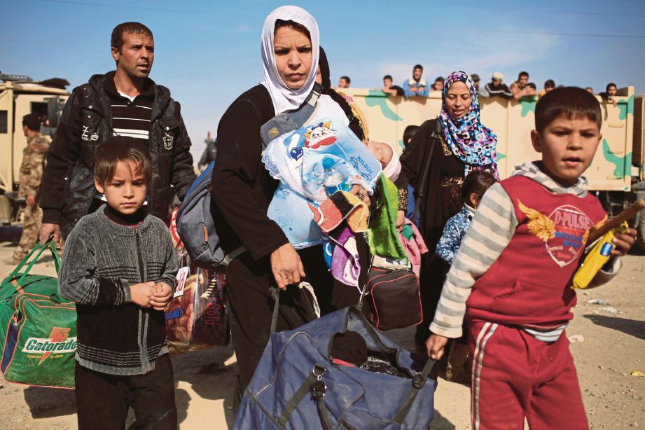 SEORANG wanita yang melarikan diri dari Mosul menggendong anaknya bersama anggota keluarganya yang lain berjalan menuju ke pusat pemeriksaan tentera khas Iraq di timur Mosul, semalam. - Reuters