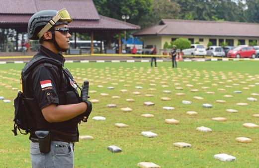 SEORANG anggota polis berkawal berhampiran bungkusan ganja yang disusun di atas padang di ibu pejabat polis di Jakarta.