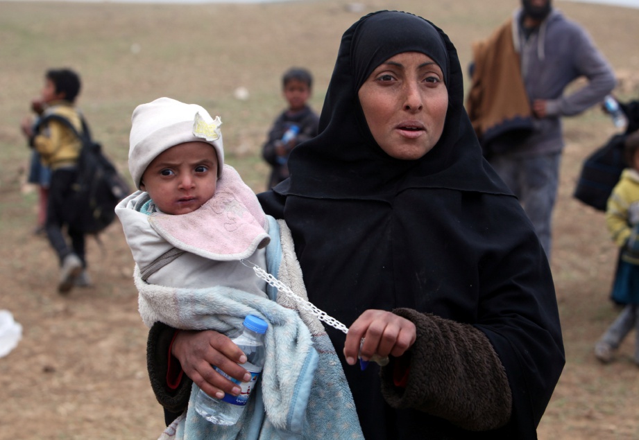 SEORANG wanita mendukung anaknya ketika meninggalkan kediamannya di barat laut Mosul apabila tentera Iraq meningkatkan serangan terhadap Daish di kawasan itu, semalam.  - Reuters 