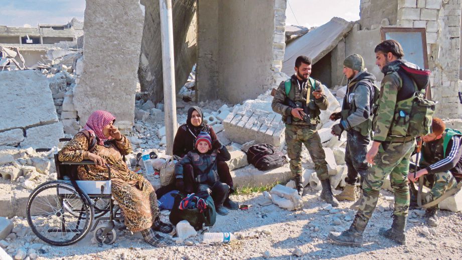 SEKUMPULAN tentera Syria berdiri di sebelah beberapa penduduk Sheikh Saeed, daerah terbesar di timur Aleppo selepas mereka menawannya daripada kumpulan penentang. - AFP