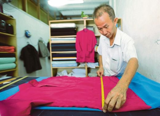 LIN menyiapkan baju Melayu   ditempah pelanggan  di kedai jahitnya.