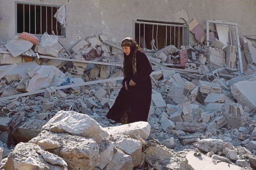 SEORANG wanita meredah runtuhan bangunan selepas serangan tentera rejim Syria di Dael, Deraa, semalam.  Kawasan itu dikuasai kumpulan penentang Bashar.  