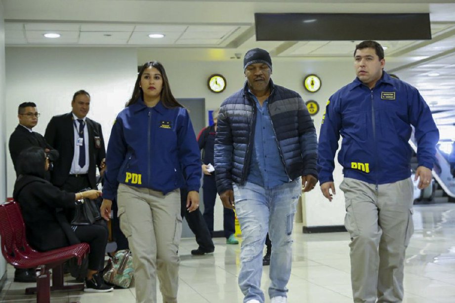  TYSON (tengah) diiringi polis imigresen di lapangan terbang Chile. FOTO/AFP 