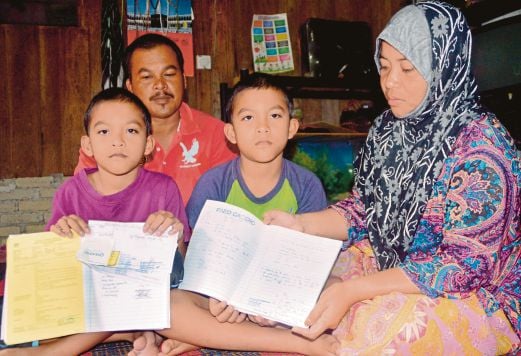  PASANGAN  kembar, Muhammad Azizi (kiri) dan Muhammad Alimi  menunjukkan dokumen rawatan sakit jantung mereka sambil diperhatikan Siti Zawiyah  dan Aliff di rumah mereka di Kampung Nyiur Chabang, Langkawi, semalam.