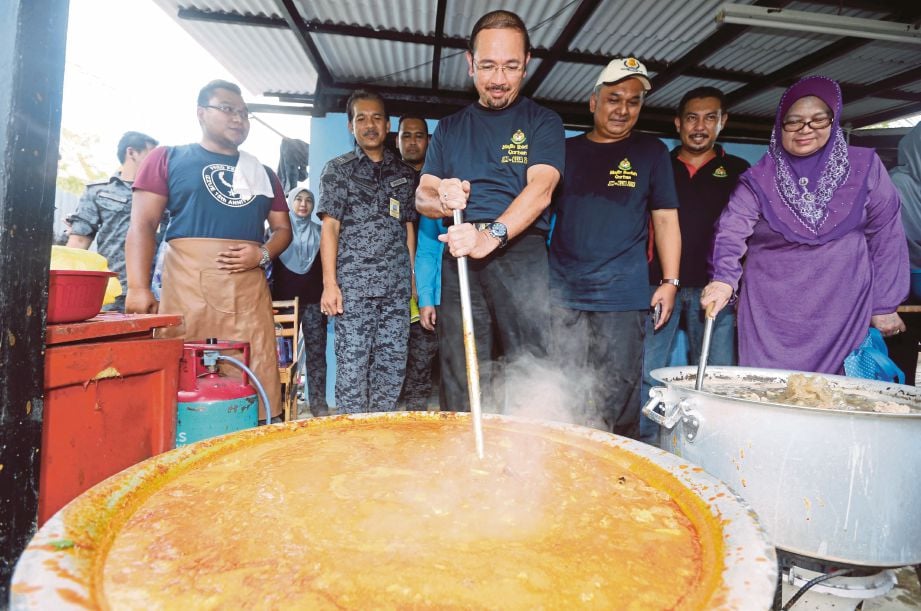  Mustafar (tengah) memasak kari daging selepas majlis korban di Depoh Tahanan Imigresen KLIA, Sepang, semalam.