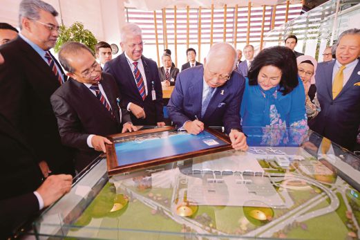 Najib diiringi Rosmah menandatangani potret Lapangan Terbang Antarabangsa ISG selepas merasmikan ruang istirahat baru, semalam.