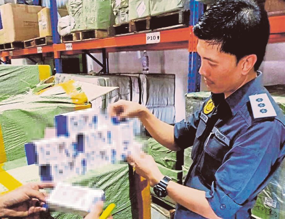 PEGAWAI penguat kuasa KPDNKK memeriksa barangan tiruan yang dirampas di Jalan Petaling.