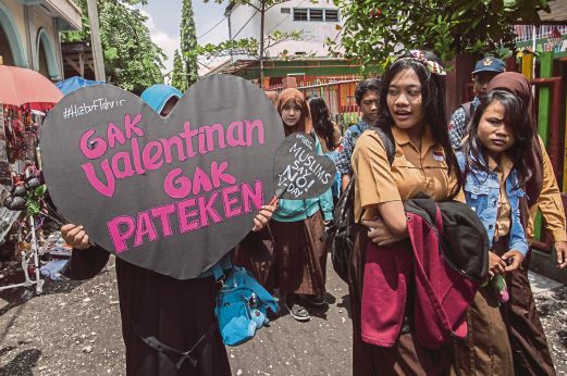 ANGGOTA Hizbut Tahrir membawa sepanduk di perhimpunan membantah sambutan Hari Valentine di luar sebuah sekolah di Surabaya.