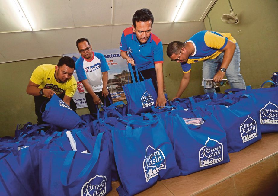 Sukarelawan Harian Metro bergotong-royong mengangkat barang sumbangan.