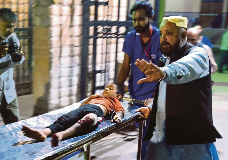SUKARELAWAN mengusung seorang kanak-kanak yang cedera di sebuah hospital di Karachi.  - AFP