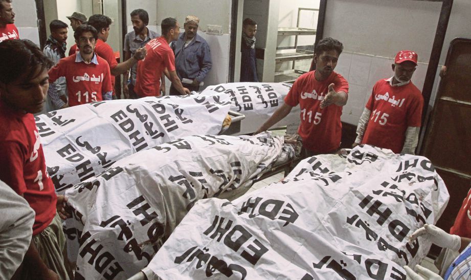SUKARELAWAN menyusun mayat di sebuah rumah mayat di Karachi. - AFP 