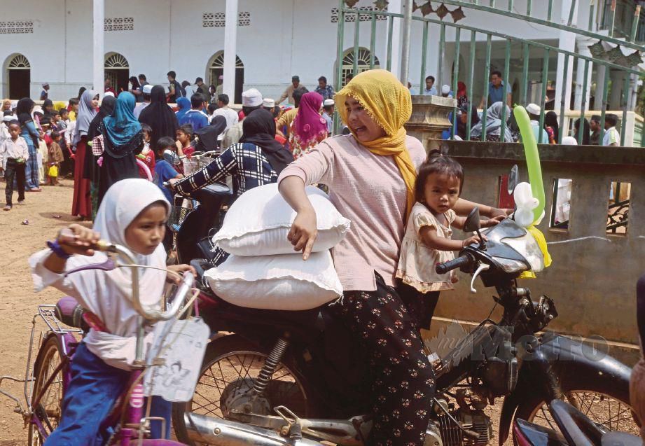 SEORANG wanita Kemboja membawa bantuan makanan menaiki motosikal bersama anaknya.