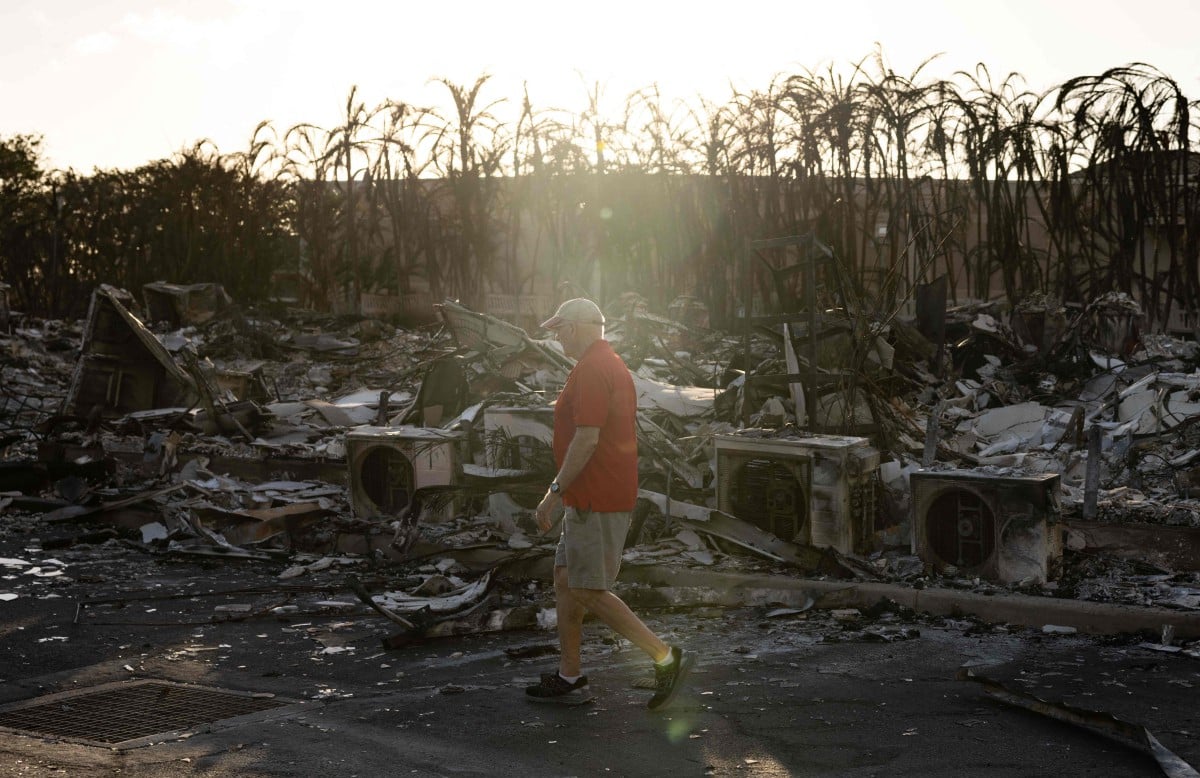 PENDUDUK melalui kompleks apartment yang musnah dalam kebakaran di Lahaina, barat Maui. FOTO AFP.