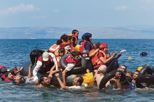 PELARIAN Syria dan Afghanistan dilihat di atas dan sekitar bot getah mereka yang bocor kira-kira 100 meter sebelum tiba di Pulau Lesbos, Greece, semalam.  