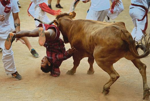 SEORANG peserta larian terpelanting ditanduk seekor lembu di festival   Pamplona, semalam. 