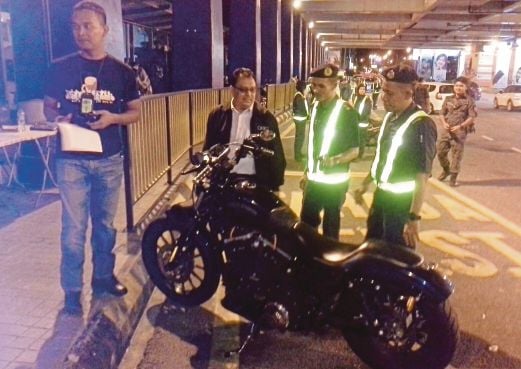  MD Ziki (kiri)  menunjukkan motosikal Harley Davidson yang dirampas.