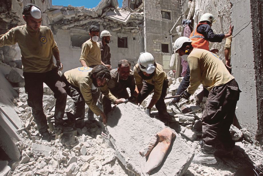 PENDUDUK dan petugas sukarelawan berusaha mencari mangsa yang mungkin tertimbus dalam runtuhan bangunan selepas serangan udara di bandar Ariha di wilayah Idlib, semalam. - Reuters