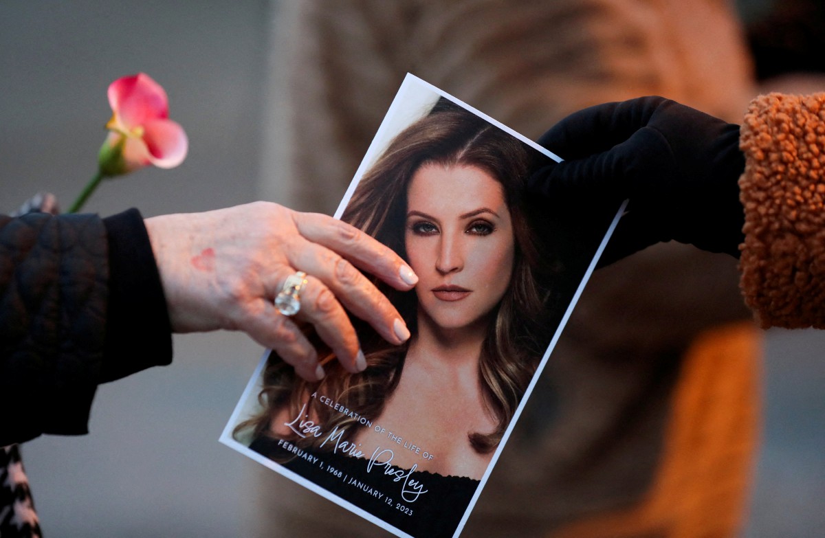 PEMINAT memegang gambar Lisa Marie Presley ketika menghadiri memorial penyanyi itu di rumah agam Graceland, Januari lalu. FOTO Reuters.
