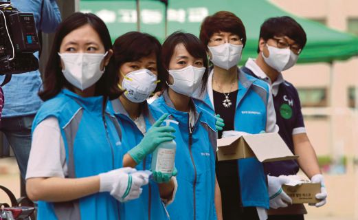  PEKERJA kesihatan Korea Selatan memakai topeng bedah ketika menanti untuk memeriksa suhu mereka yang datang untuk menjalani pemeriksaan di Seoul, semalam.  