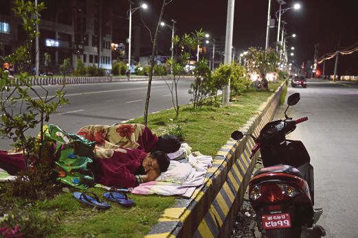 PENDUDUK setempat tidur di pembahagi jalan raya di Kathmandu, semalam.