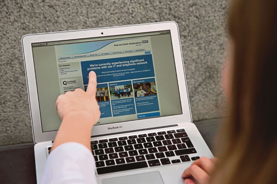 SEORANG wanita menunjukkan laman web NHS yang memaklumkan penggunanya mengenai masalah rangkaiannya. - AFP 