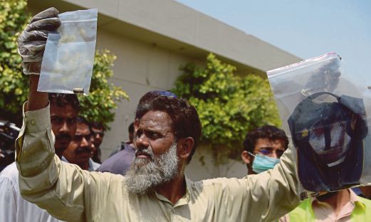 ANGGOTA polis Pakistan berpakaian preman menunjukkan bahan bukti di tempat kejadian.