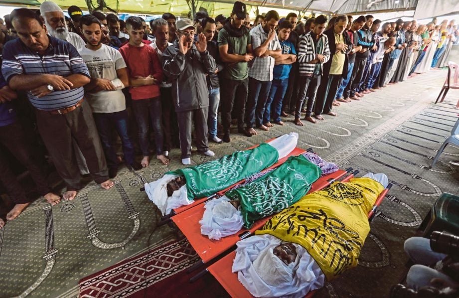 TIGA jenazah korban serangan Israel disembahyangkan penduduk Palestin sebelum dikebumikan di Gaza, semalam. FOTO  AFP