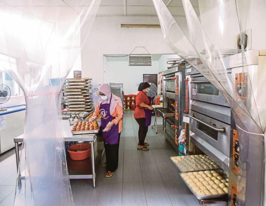 PENGUSAHA produk PKS, Sarimah Jantan (kiri) menyiapkan roti yang baru dibakar, di premisnya  Hidayah Cookies di  Sungai Kandis, Selangor.  FOTO OSMAN ADNAN 