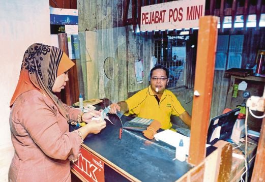 MOHD Rosdi melayan pelanggannya, Zainun Yahya Sabri, 50, yang ingin membayar bil elektrik di Kampung Palekbang, Tumpat. 