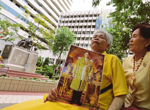 DUA penduduk Thai dengan gambar Bhumibol menyertai acara keagamaan di luar Hospital Sirira di Bangkok, semalam. 
