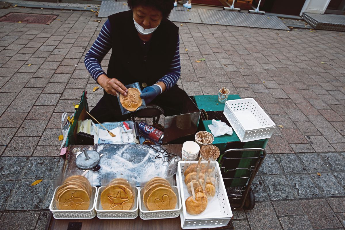 PENJAJA makanan jalanan menjual biskut sarang lebah dalgona. FOTO EPA 