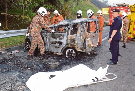 ANGGOTA bomba memeriksa  kereta dinaiki mangsa yang terbakar selepas terbabas ke bahu jalan, semalam.