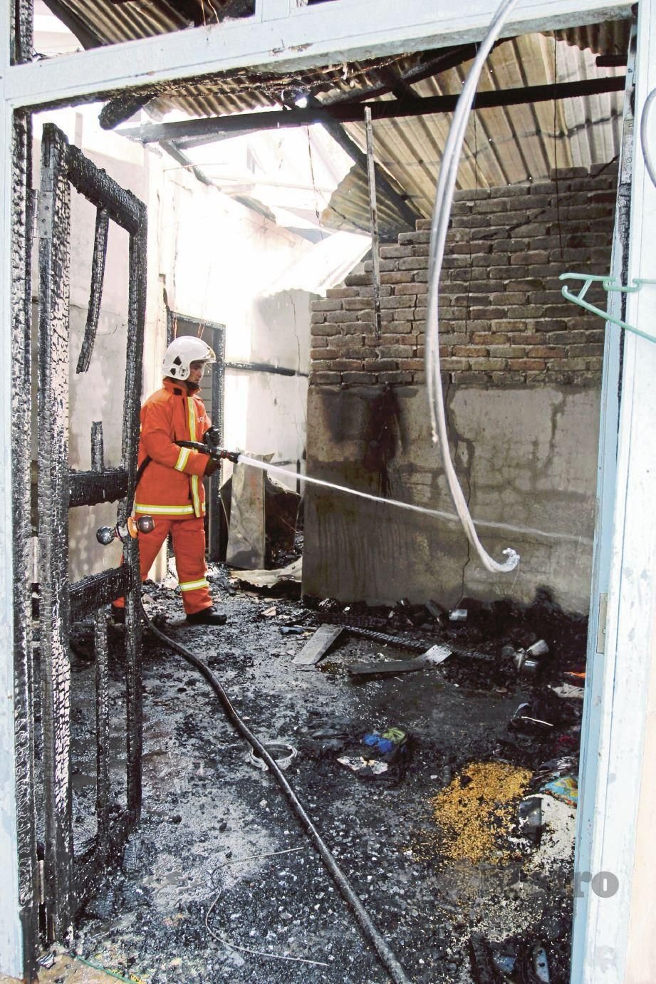 ANGGOTA bomba   memadam api di bahagian ruang tamu dalam  kebakaran rumah di Kampung Padang Pohon Tanjung. 