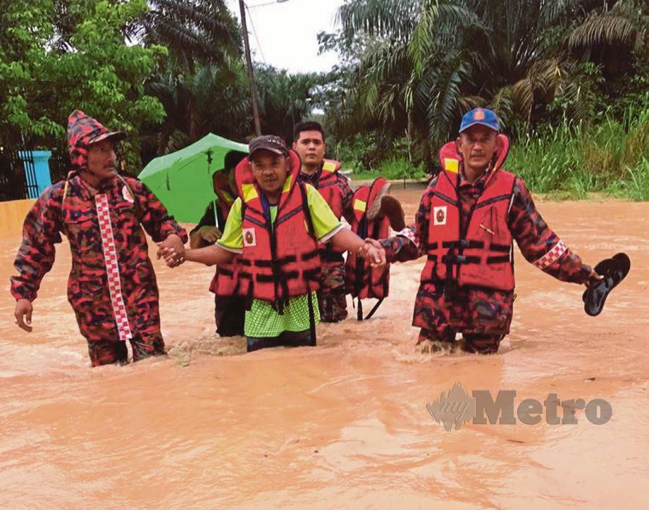ANGGOTA bomba membantu memindahkan mangsa banjir di Kampung Usaha Jaya dan Sungai Karas, Labis. 