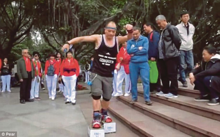 XIAO berjalan dengan kasut yang diikat besi seberat 75 kilogram di sebuah taman di Shenzhen, China. - Agensi