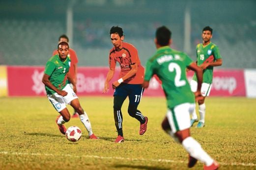 PEMAIN FELDA United Ahmad Syamim Yahya (tengah) cuba melepasi pertahanan Bangladesh.