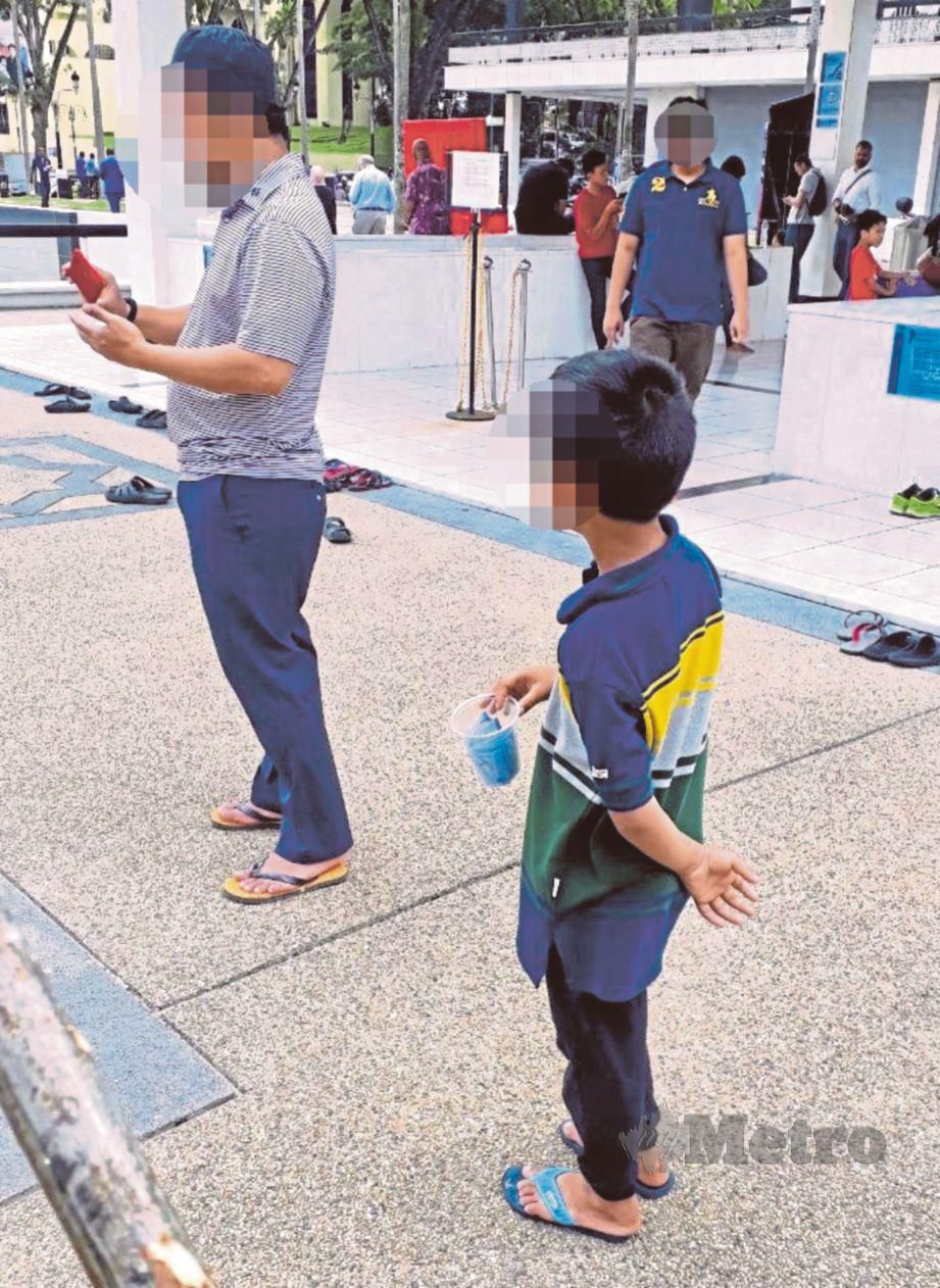 SEORANG wanita mendukung anaknya meminta sedekah di pekarangan Masjid Negara.