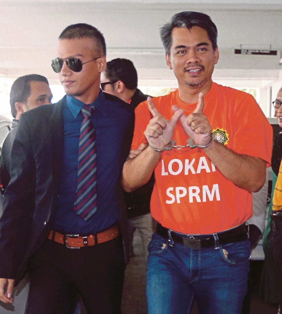 PEGAWAI SPRM mengiringi Mohd Azis di Mahkamah Majistret Kota Kinabalu.