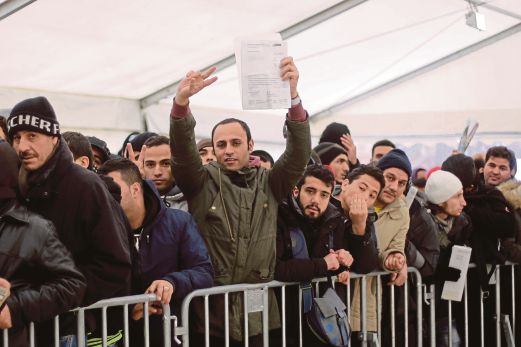 SEORANG pendatang menunjukkan dokumennya ketika menunggu bersama ratusan yang lain untuk mendaftar di Pejabat Hal Ehwal Kesihatan dan Sosial, Berlin.