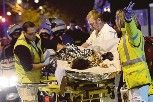 PASUKAN penyelamat membantu seorang mangsa yang cedera dalam serangan di dewan konsert di Bataclan, Paris, semalam.   