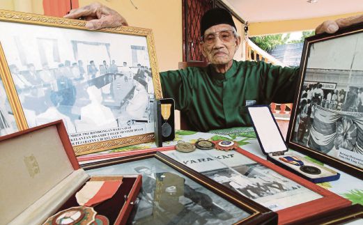 MOHD Tahir menunjukkan gambar kenangan beliau di awal pembentukan Malaysia.