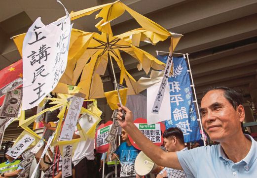 Penyokong pro-China memegang payung yang koyak menyindir pergerakan prodemokrasi di Hong Kong.
