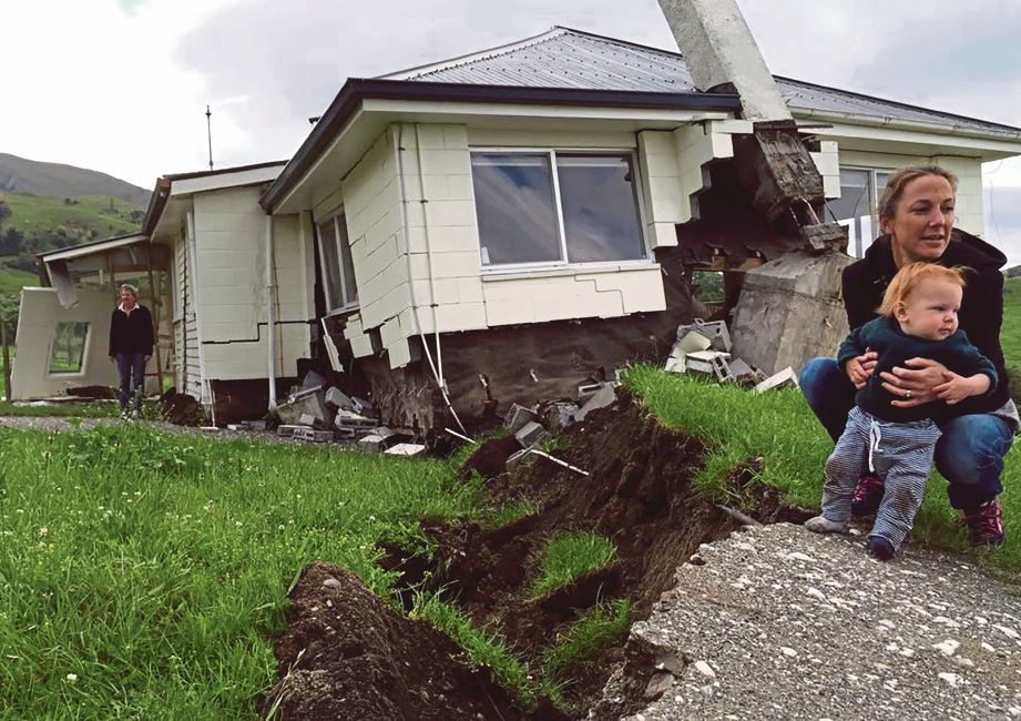 SEORANG wanita bersama  bayinya di depan rumah mereka yang rosak teruk akibat gempa bumi. - AFP