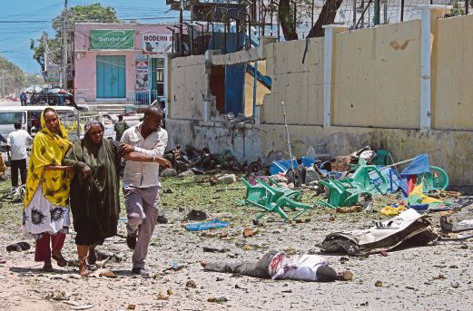SEORANG wanita yang cedera dipapah melintasi satu mayat di luar Kementerian Pelajaran di Mogadishu, semalam.  