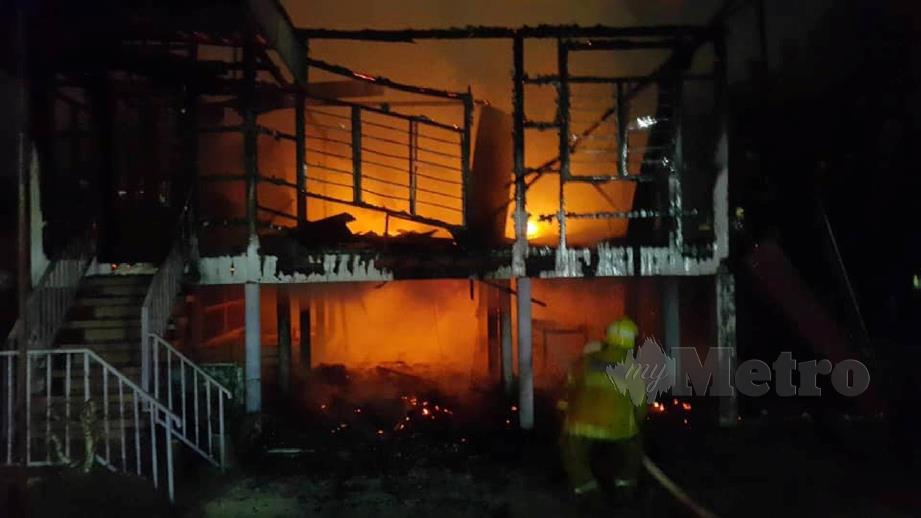 ANGGOTA bomba berusaha memadamkan kebakaran rumah di Lorong Kilang Kopi Lama. FOTO Ihsan Bomba