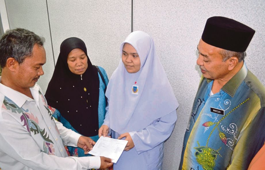 MD Noor Osman (kiri) dan isteri, Fatimah Abu Bakar melihat slip SPM yang diperoleh Noor Fatini Aina sambil diperhatikan Pengetua Sekolah Menengah Kebangsaan Gurun Mazuki Yahaya. 
