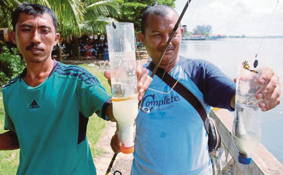 MOHD Zaini (kiri) dan Hamid menunjukkan ikan belanak yang dipancing.