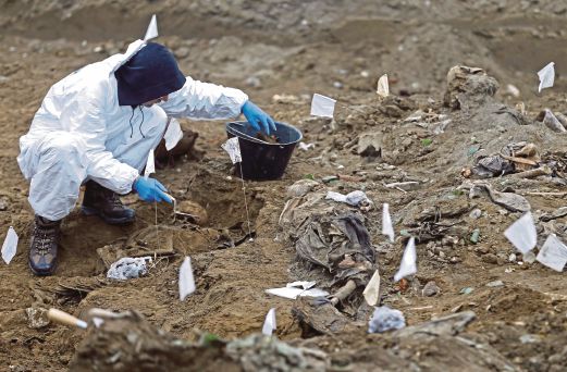 PAKAR forensik mencari sisa mayat manusia ketika penggalian semula kubur besar-besaran di Kozluk.