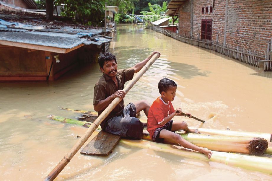 SEORANG penduduk dan anaknya menaiki rakit batang pisang di kampung Kedungwaringin di Bekasi di Jawa Barat yang dilanda banjir kelmarin. - Antara 